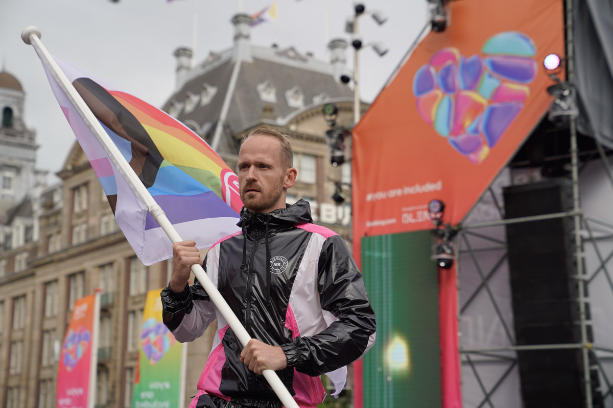 man with beard holding a pride flag