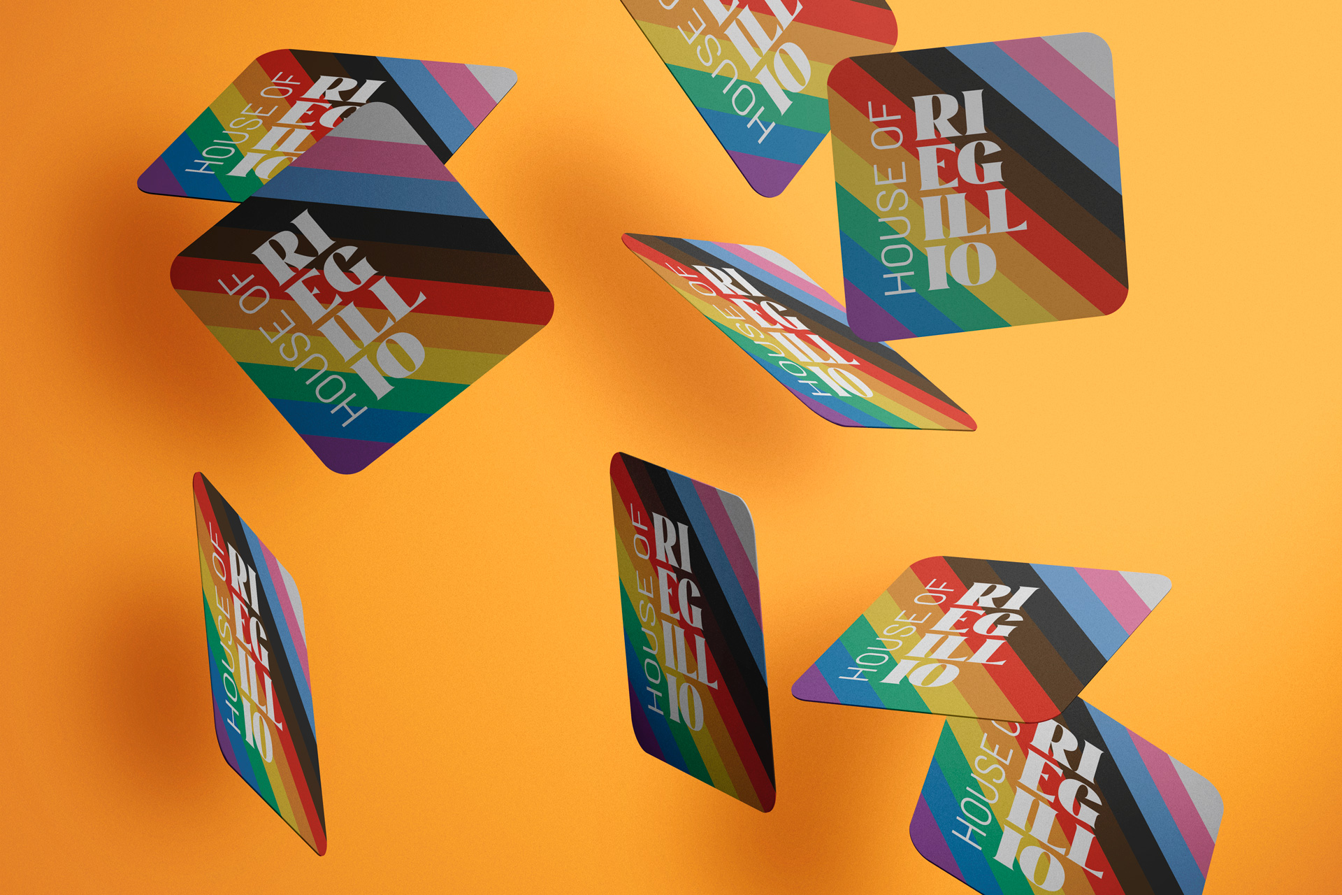 Multiple colorful coasters with diagonal stripes in rainbow colors and the text 'HOUSE OF REGILLO' on an orange background.
