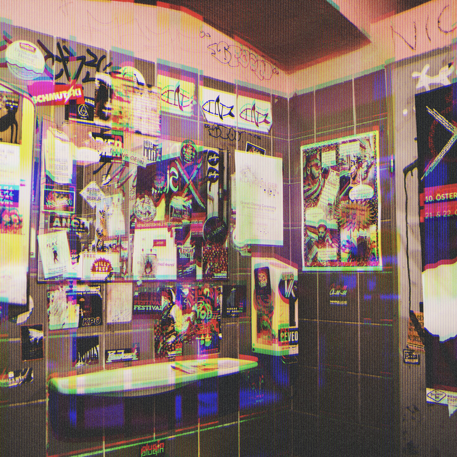 Bathroom wall covered with numerous colorful posters, flyers, and graffiti stickers, creating a busy, urban collage.