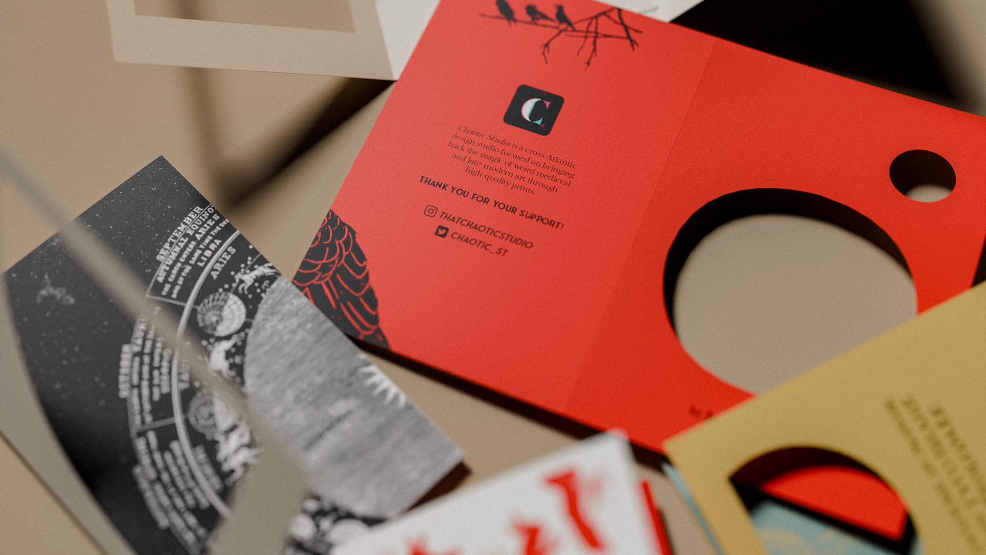 Close-up of colorful printed cards with cut-out circles, featuring designs and text about Chaotic Studio.