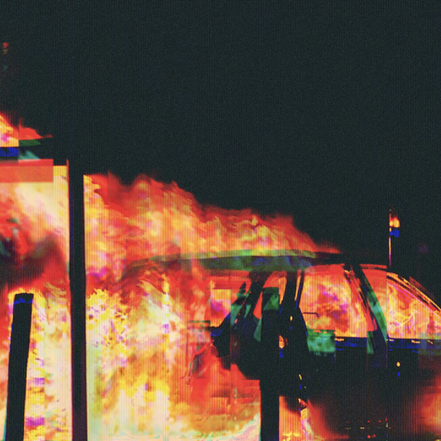 Car engulfed in bright orange and yellow flames at night with dark surroundings.