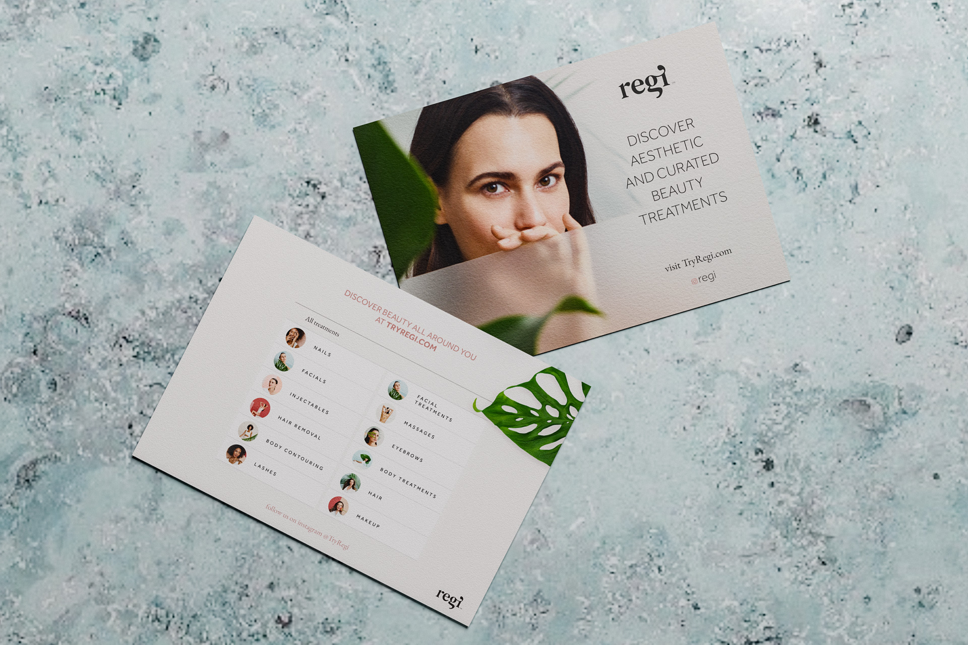 Two postcards on a textured surface, one showing a woman partly hidden behind a green leaf with the text 'regi DISCOVER AESTHETIC AND CURATED BEAUTY TREATMENTS', the other listing beauty treatments like nails, facials, injectables, and makeup with small circular photos.